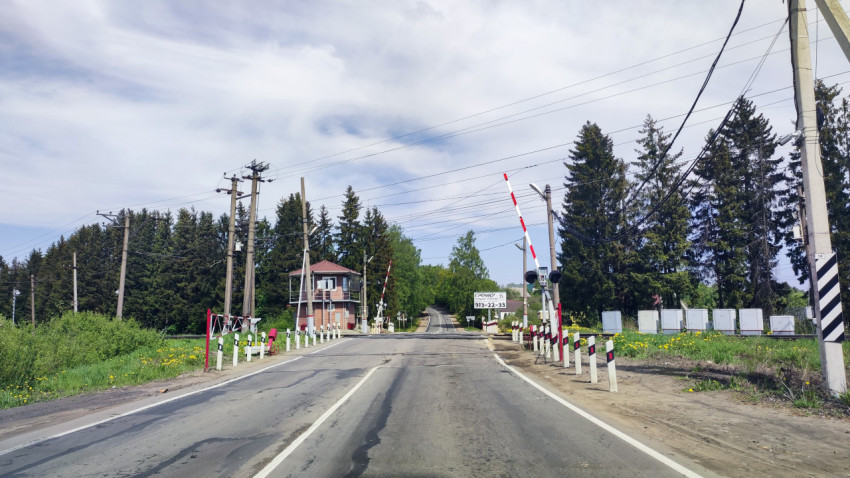 Железнодорожный переезд с поднятыми шлагбаумами и будкой дежурного