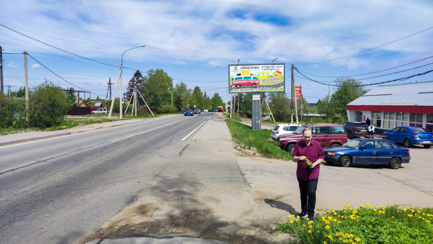 Дорога с рекламным щитом и жилой застройкой в пригороде