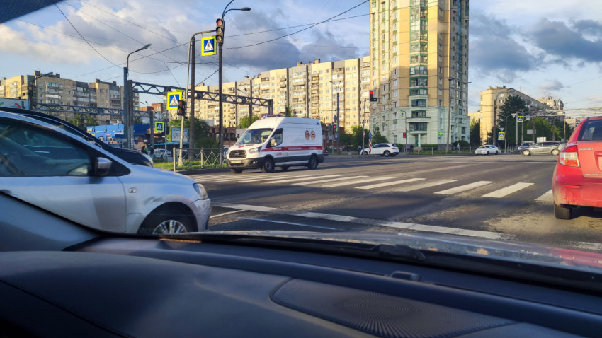Перекрёсток с пешеходным переходом и машиной скорой помощи на фоне жилых домов