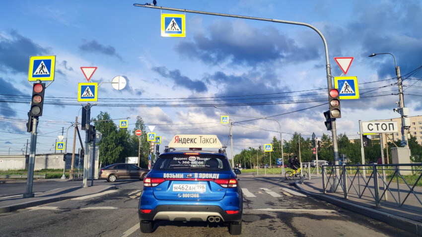 Перекрёсток с множеством дорожных знаков и автомобилем такси у стоп-линии