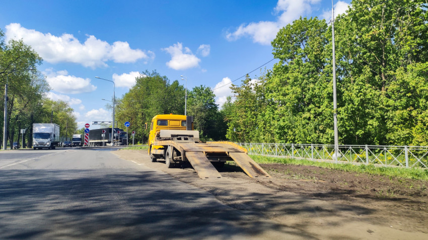 Эвакуатор с опущенными трапами у обочины на пригородной дороге