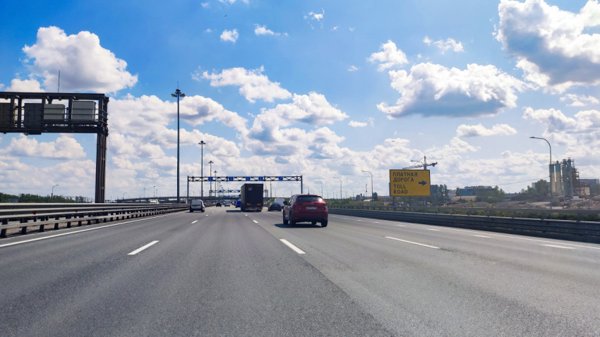 Магистраль с порталами и жёлтым щитом «Платная дорога / Toll road»