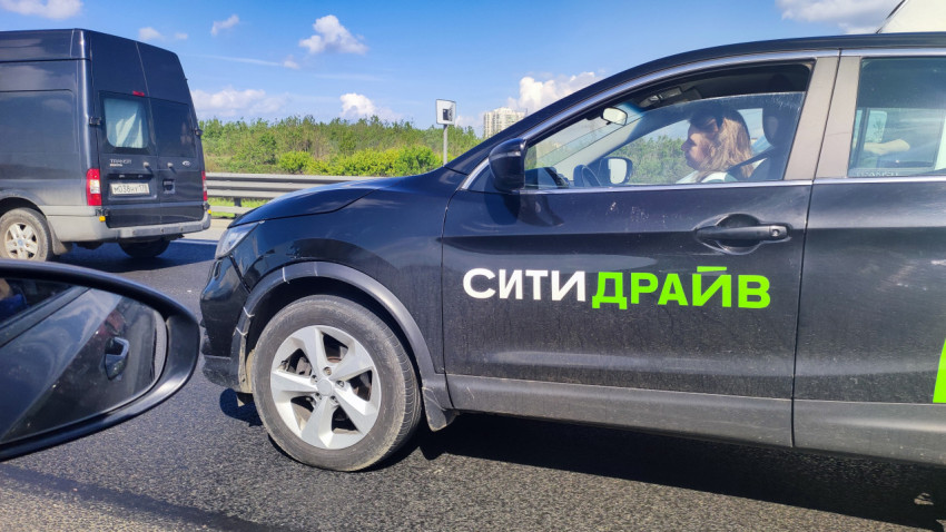 Каршеринг-авто в потоке рядом с фургоном на магистрали