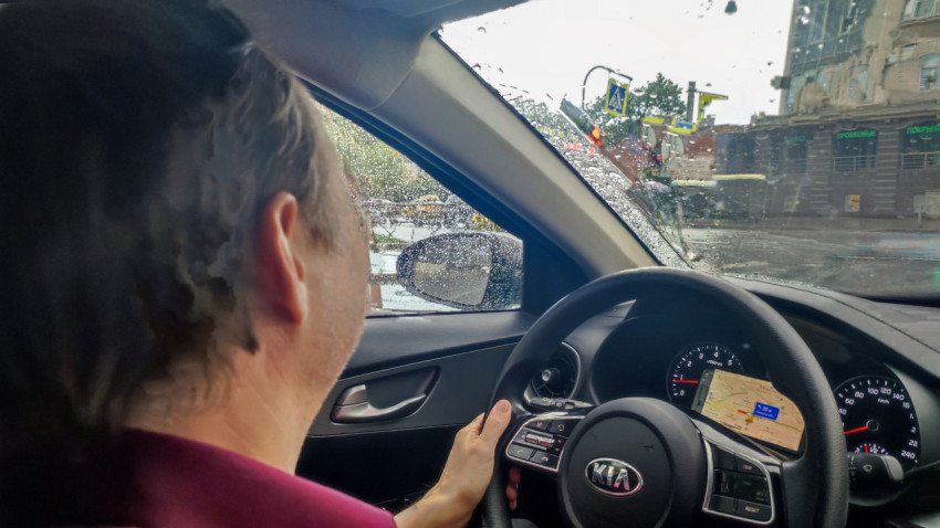 Водитель за рулём автомобиля Kia в дождливый день