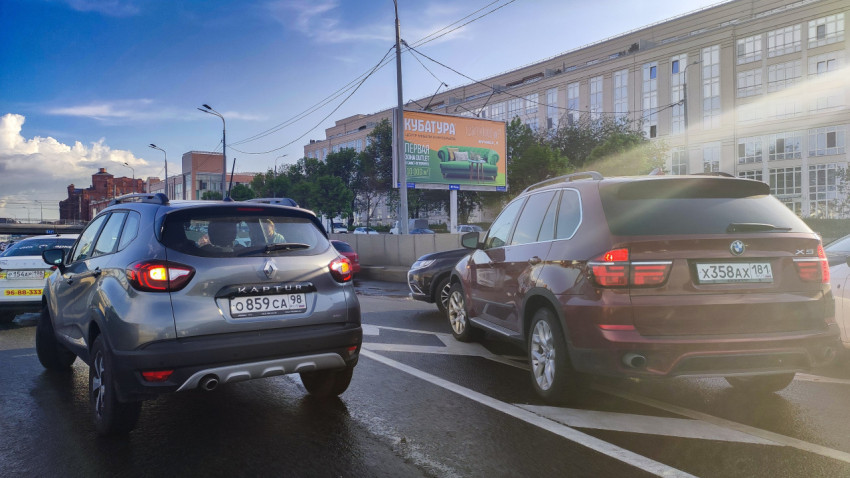 Автомобили на улице рядом с билбордом и зданием