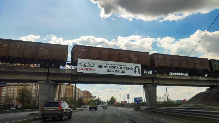 Грузовой поезд на железнодорожном мосту над автомагистралью