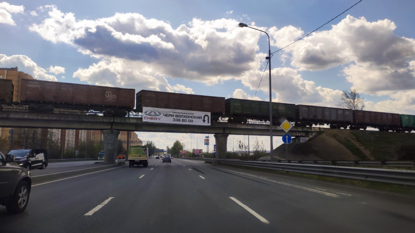 Грузовой поезд на железнодорожном мосту над трассой