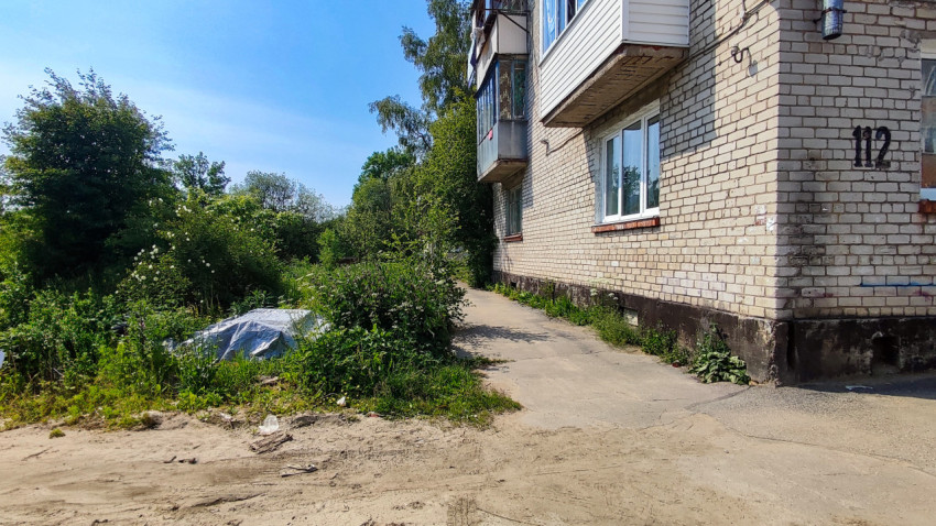 Заросшая территория у кирпичного жилого дома