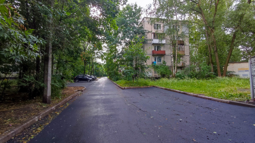 Асфальтированная дворовая территория с жилым домом и деревьями