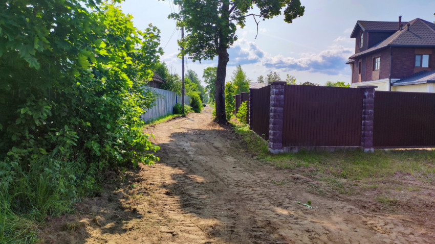 Земляная дорога вдоль жилых заборов и загородных домов