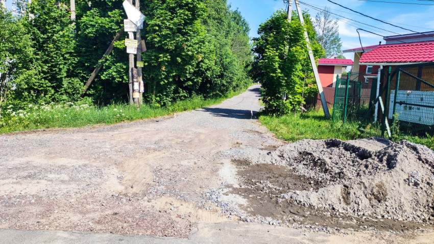 Гравийная дорога в жилом поселке с примыкающей асфальтированной улицей