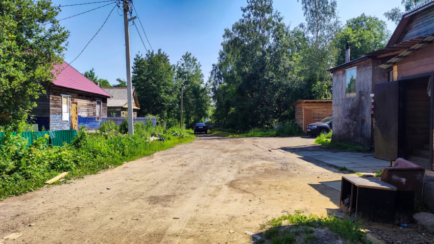 Деревенская улица с деревянными домами и электропроводами
