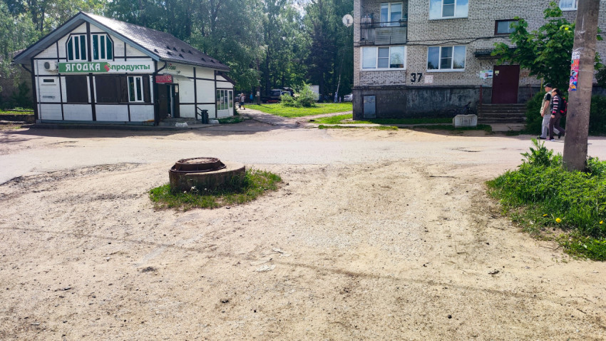 Выступающий люк на дворовой дороге рядом с жилым домом