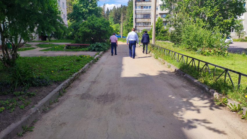 Придомовая дорога с тротуаром и группой людей на фоне жилых домов