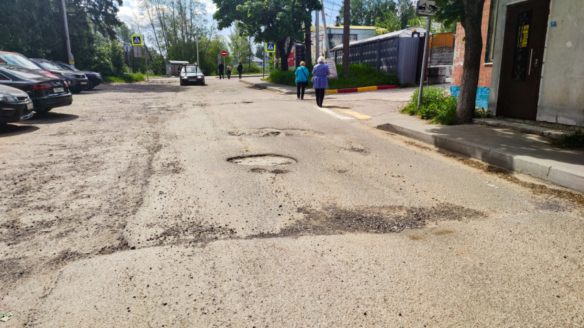Дорожное покрытие с выбоинами и пешеходами на городской улице