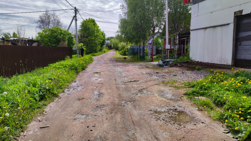 Грунтовая дорога с лужами вдоль частных домов