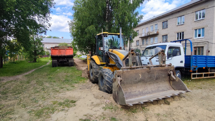 Строительная техника и самосвал во дворе жилого квартала