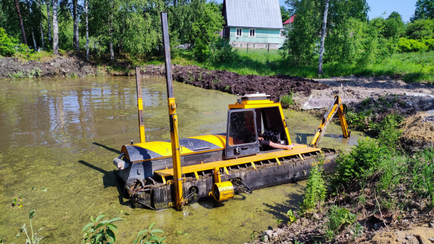 Амфибийный экскаватор очищает пруд