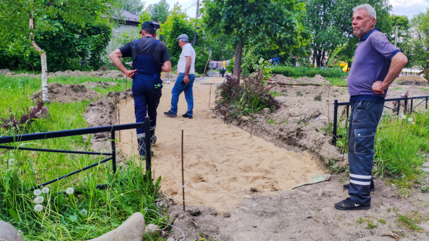 Рабочие проверяют процесс устройства песчаной дорожки