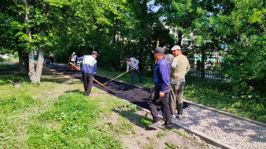 Рабочие укладывают асфальт на дворовой дорожке
