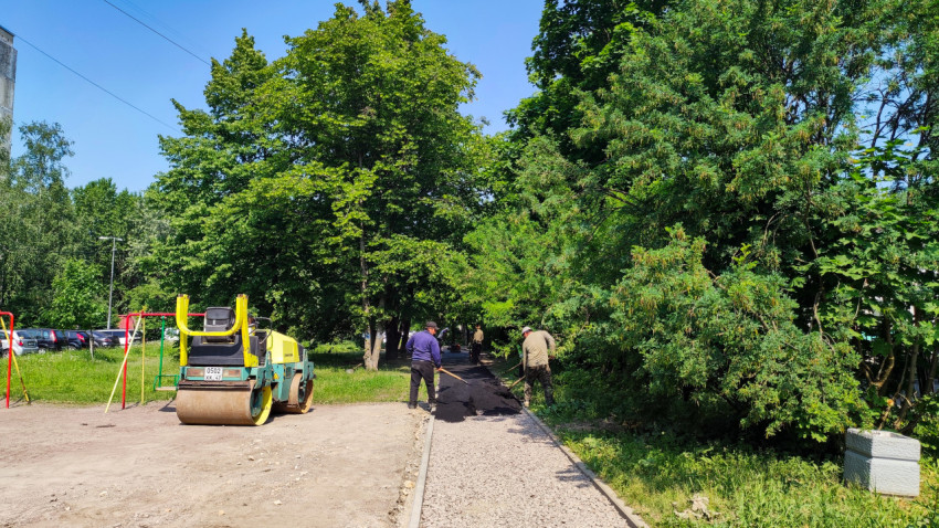 Рабочие распределяют асфальт на пешеходной дорожке