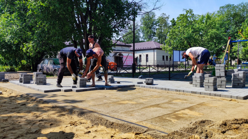 Рабочие укладывают тротуарную плитку на подготовленное основание
