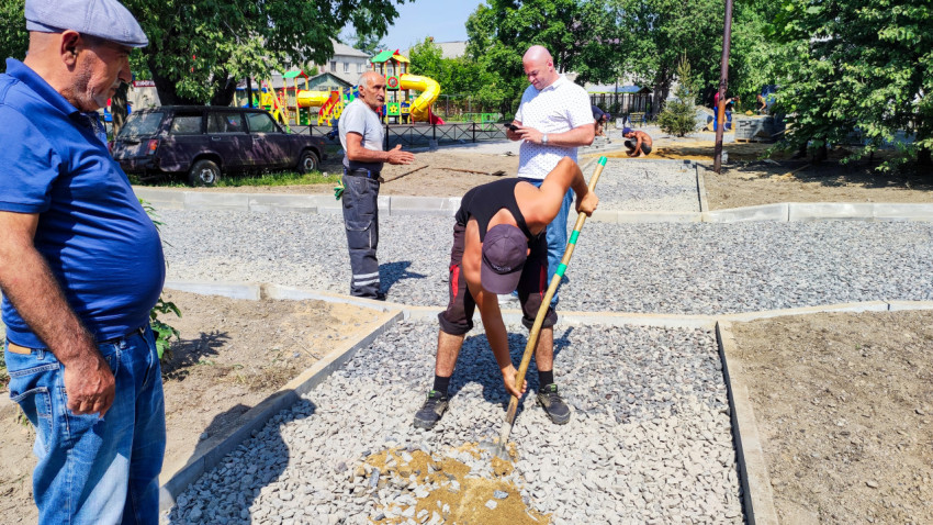 Рабочие выравнивают щебень на тротуарной дорожке