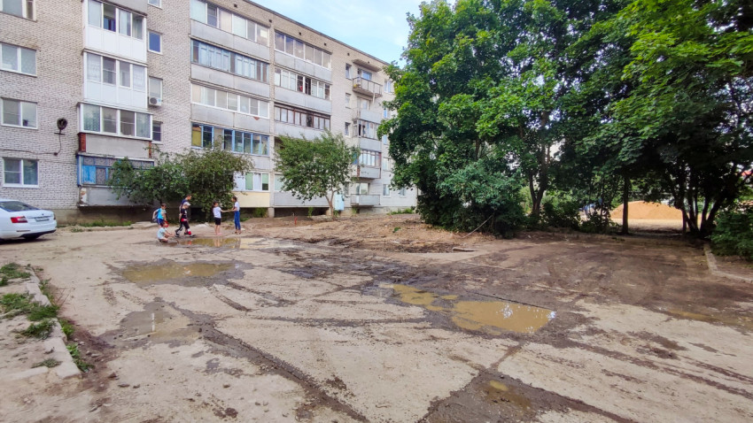 Двор жилого дома с детьми на неасфальтированной площадке