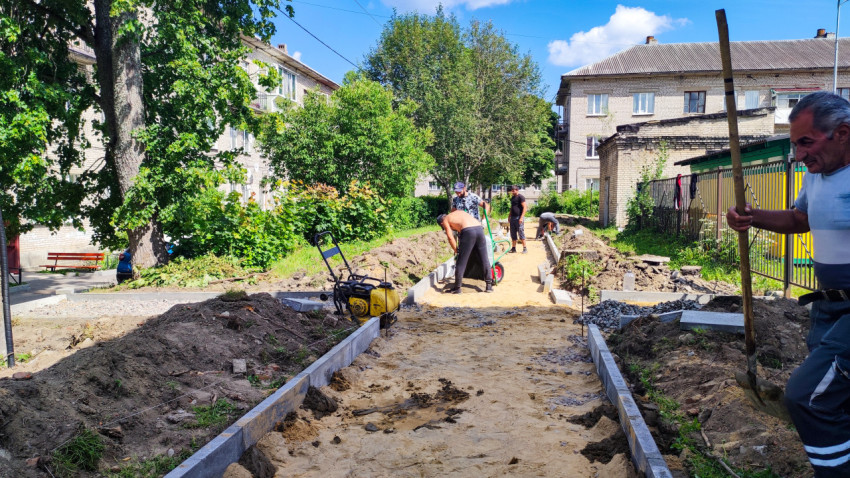 Рабочие укладывают бордюр и готовят основание дорожки