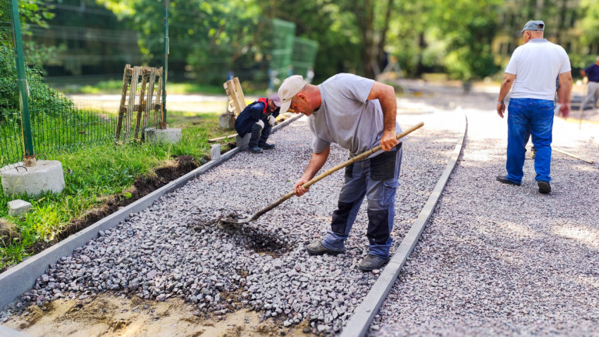 Рабочий выравнивает гравий при устройстве дорожного покрытия