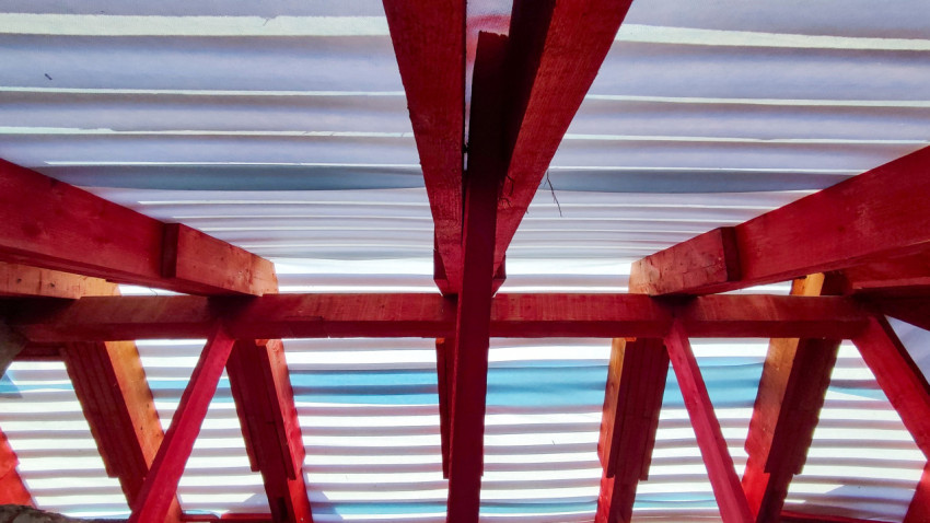 Красные деревянные стропила крыши под временным покрытием