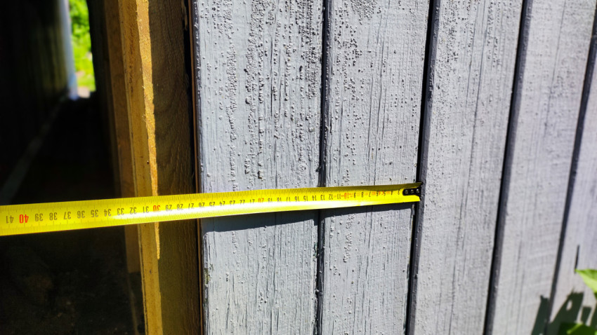 Замер расстояния на деревянной стене здания