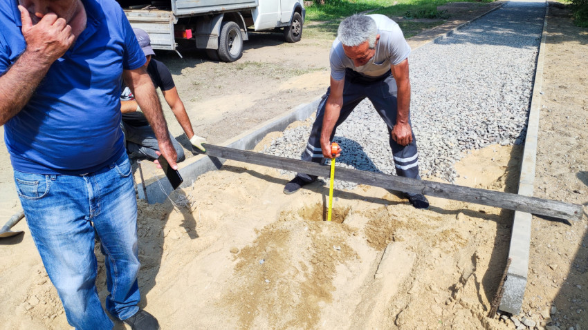 Рабочие измеряют глубину ямы на стройплощадке