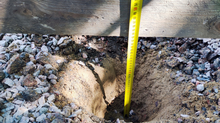 Измерение глубины выкопанной ямы при помощи рулетки