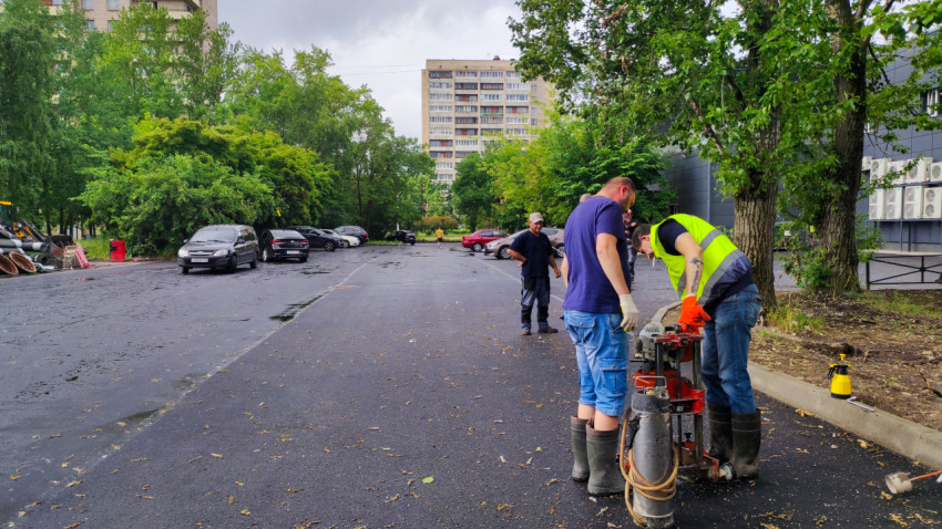Рабочие проводят обследование асфальта во дворе жилого квартала
