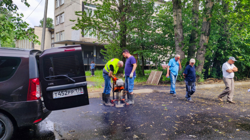 Рабочие бурят асфальт для отбора проб во дворе жилого дома