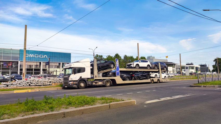 Автовоз с новыми машинами на городской дороге