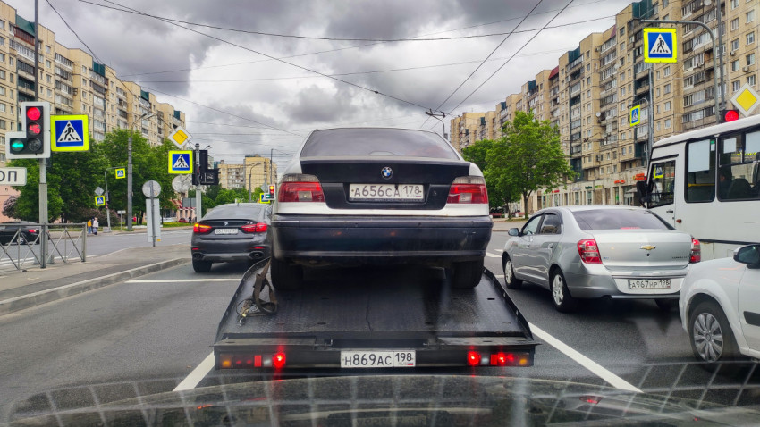 Автомобиль BMW на эвакуаторе в городском потоке