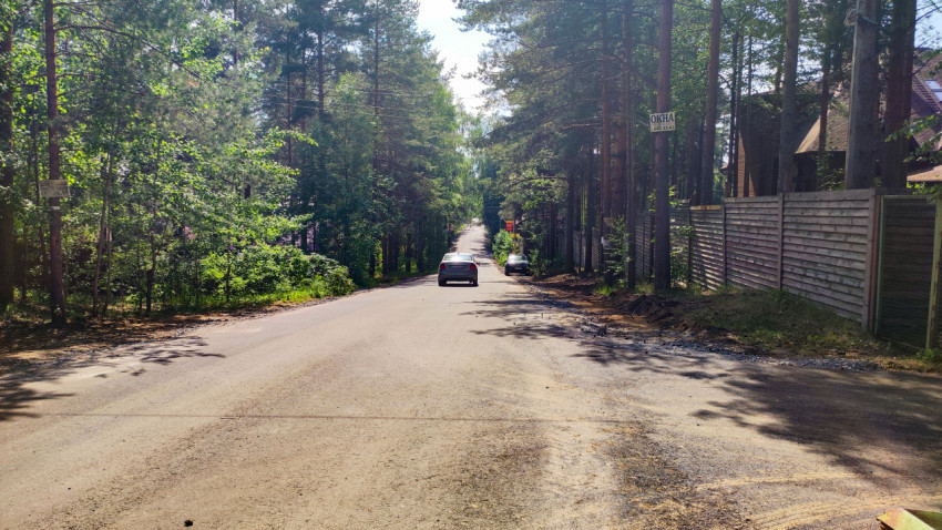 Асфальтированная дорога среди леса с движущимися автомобилями