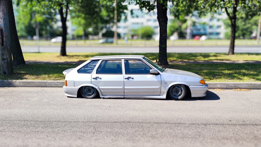 Белый автомобиль с тюнингом, припаркованный у тротуара