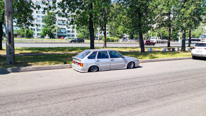 Белый автомобиль с заниженным клиренсом на стоянке у жилого дома