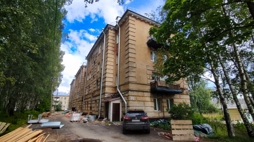 Кирпичный жилой дом советской застройки в окружении деревьев