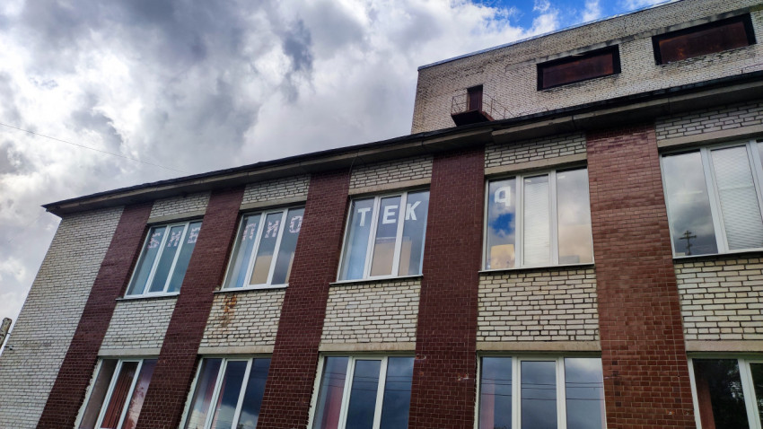 Фасад кирпичного здания с витражами и буквами на окнах