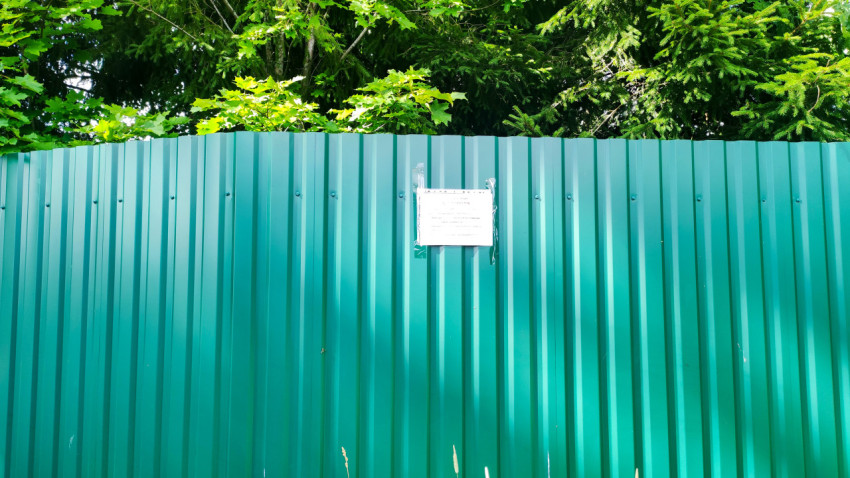 Объявление на зелёном металлическом заборе