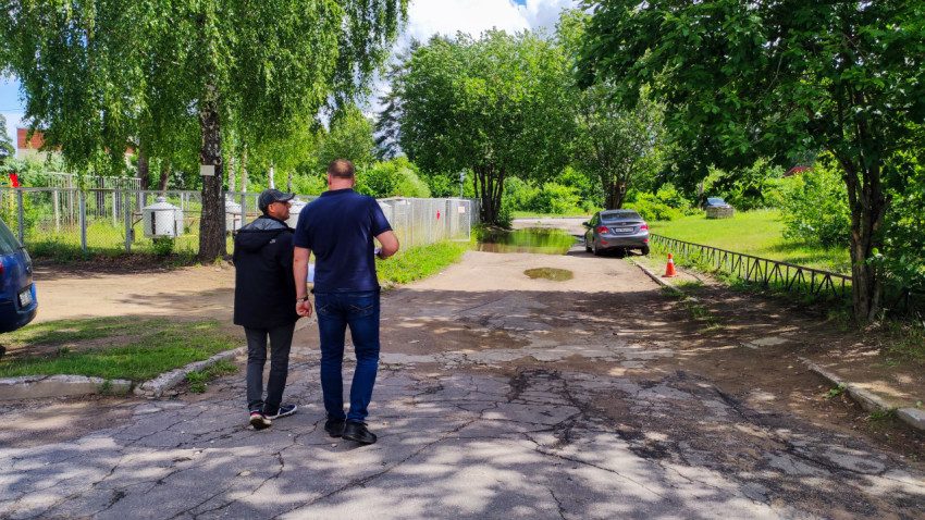 Осмотр повреждённой асфальтовой дороги с лужами