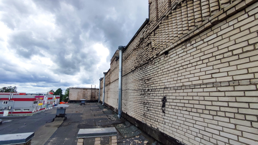 Кирпичная стена здания с элементами разрушения и вентиляционными трубами