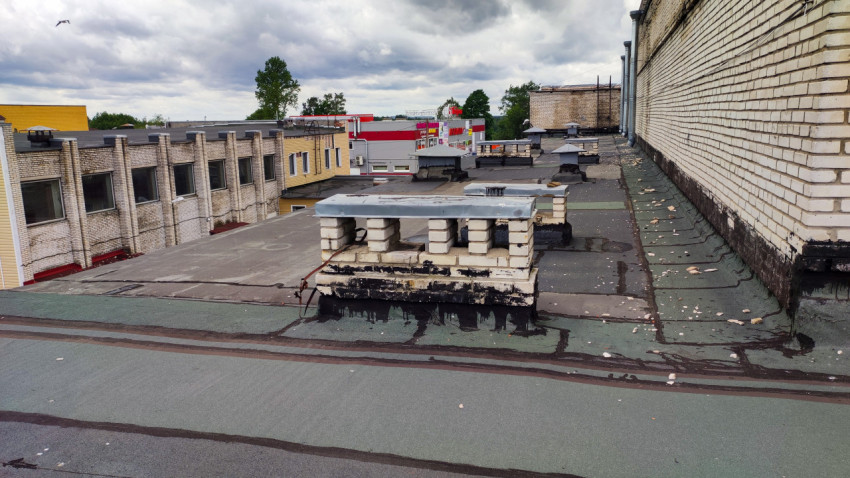 Плоская крыша с вентиляционными конструкциями и стеной здания