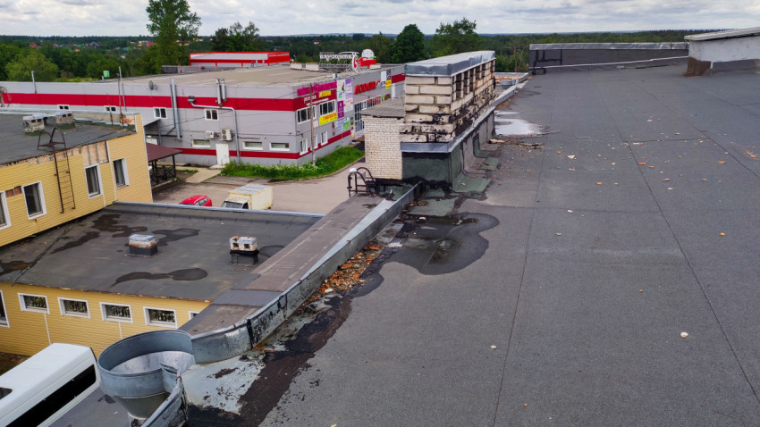 Плоская крыша здания с видимыми следами влаги и кирпичными конструкциями