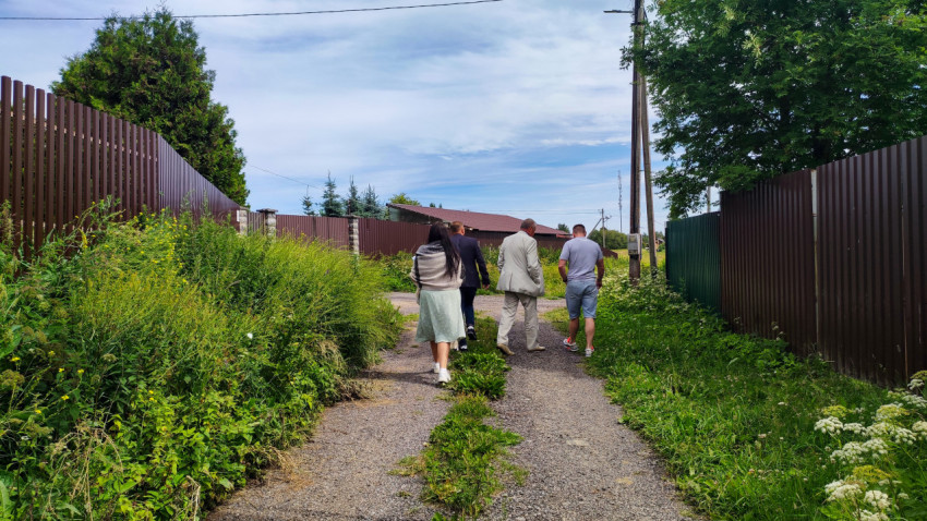 Группа людей идёт по загородной улице с ограждениями