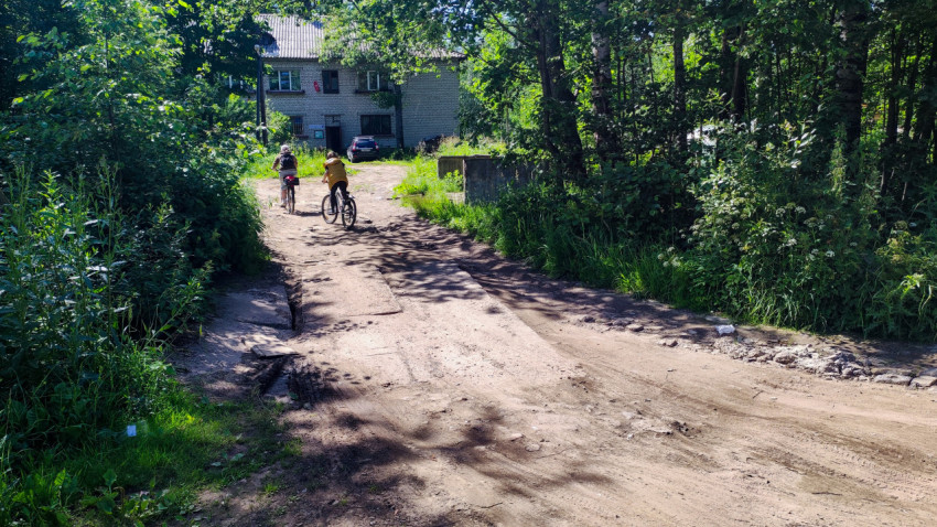 Деревенская дорога и велосипедисты у жилого дома